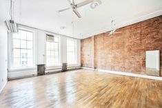 an empty room with wood floors and brick walls