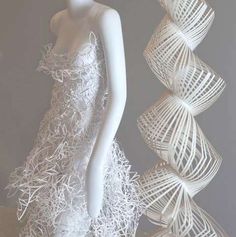 a white mannequin is standing next to some paper sculptures that are stacked on top of each other