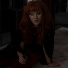 a woman with red hair is sitting on the floor