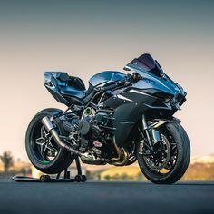 a black motorcycle parked on the side of a road next to a field and trees