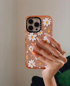 a woman holding up her phone case with flowers on it