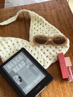 a tablet and sunglasses are sitting on a table next to a crocheted bag