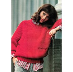 a woman in a red sweater leaning against a wall with her hand on her hip