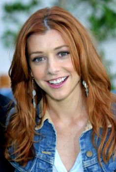 a woman with long red hair smiling at the camera