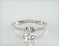 a white gold engagement ring with diamonds on the band and an oval cut center stone