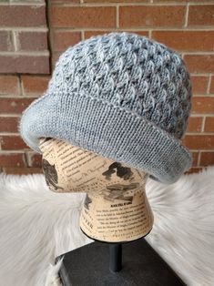 a knitted hat sitting on top of a mannequin's head in front of a brick wall