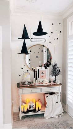 a white table topped with candles next to a wall covered in stars and witch hats