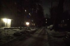 a dark street at night with snow on the ground