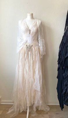 a white dress is on display next to a coat rack and jacket hanging up against the wall