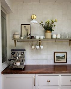 a coffee machine sitting on top of a counter next to a shelf filled with cups and saucers