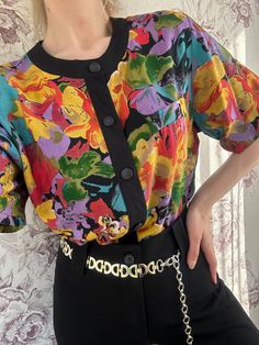 This vintage short-sleeve blouse features a vibrant multicolor floral print in bold shades of purple, yellow, red, and green. The black trim and matching buttons down the front create a striking contrast, giving the blouse a unique and artistic flair. With its relaxed fit and eye-catching design, this blouse is perfect for adding a burst of color and personality to any wardrobe. - Good vintage condition  - TAG SIZE: 36/38 - Fabric information: 100% viscose Estimated to fit XS-S-M-L based on your Red Floral Print, Vintage Short, Yellow Purple, Floral Vintage, Vintage Shorts, Blouse Vintage, Shades Of Purple, Black Trim, Fast Fashion