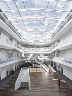 an empty building with stairs and skylights in the ceiling, while people are walking around