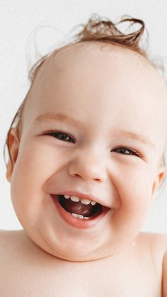 a close up of a smiling baby with no shirt on and hair in the air