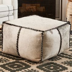 a white ottoman sitting on top of a rug next to a fire place