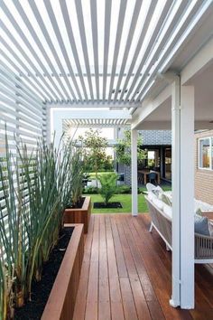 an outdoor living area with wooden flooring and white pergolated covering over it