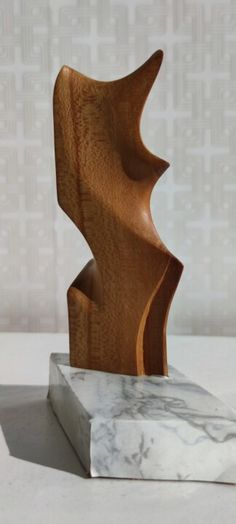 a wooden sculpture sitting on top of a marble block