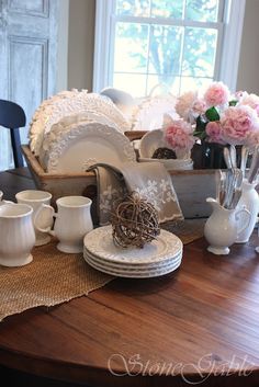 a table with plates and vases on it in front of a window, which reads 6 tips for creating a kitchen table vignette