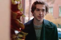 a man standing in front of a window next to a planter filled with flowers