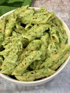 a white bowl filled with green guacamole on top of a stone counter