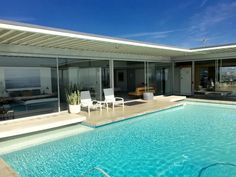 an empty swimming pool in front of a house with large sliding glass doors on the windows