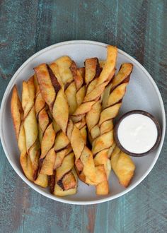 a white plate topped with french fries next to a bowl of ranch dressing