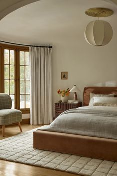 a bedroom with a large bed and two chairs in it's center area, next to a window that looks out onto the outdoors