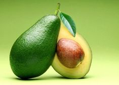 two avocados with one cut in half on a green background