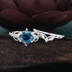 a blue diamond ring with leaves and vines around it on top of a piece of wood