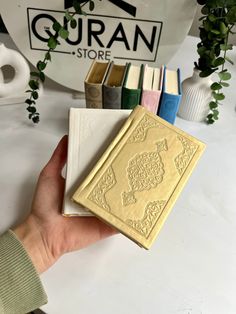 a person holding a book in front of a bunch of books on a white table