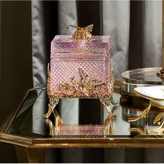 a pink box sitting on top of a glass table next to a gold plated object