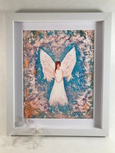 an angel painting in a white frame on a wall