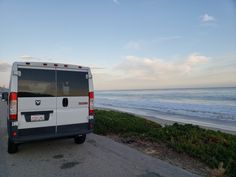 the van is parked on the side of the road next to the beach and ocean