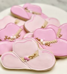 heart shaped cookies decorated with pink icing and gold trimmings on a white plate