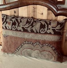 a brown and white pillow sitting on top of a wooden headboard next to a mirror