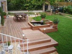 a wooden deck with steps leading up to a table and chairs in the back yard