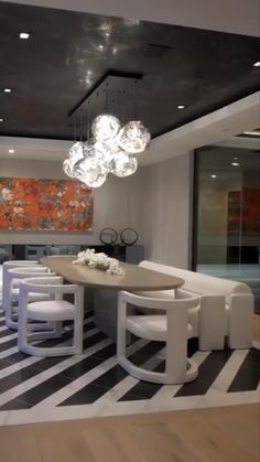 a modern dining room with white chairs and a large painting on the wall