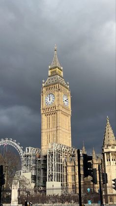 the big ben clock tower towering over the city of london under a dark sky with clouds