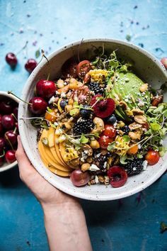 a person holding a bowl filled with fruit and nuts