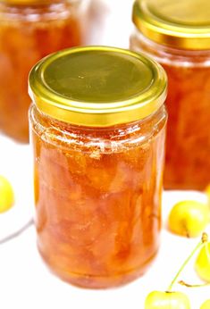 three jars filled with jelly and yellow cherries