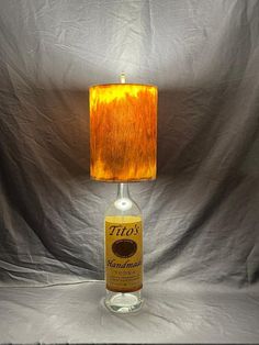 a lamp that is sitting on top of a table next to a bottle with a label on it