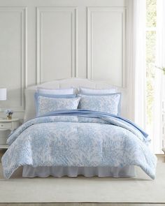 a blue and white comforter set with pillows on the headboard in a bedroom