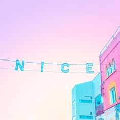 a pink and blue building with the word nice hanging from it's side on a wire