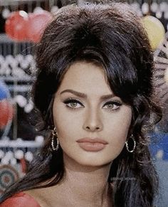 a close up of a woman with long dark hair and earrings on her head, wearing red dress