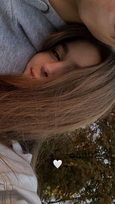 a girl with long brown hair and a white heart on her neck is looking at the camera