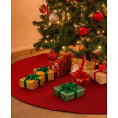 a christmas tree with presents under it on a red rug in front of a lit christmas tree