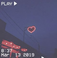 a neon sign that is on the side of a building with a heart above it