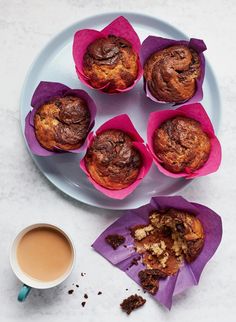 several muffins on a plate next to a cup of coffee