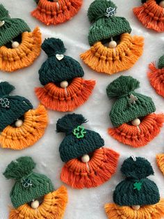 many small green and orange hats are on a table