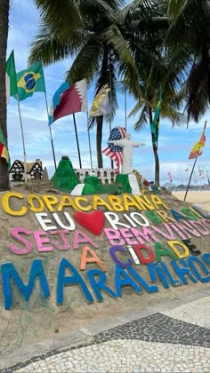 there is a sign on the beach with many flags