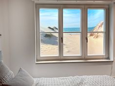 a bed sitting under a window next to a white wall